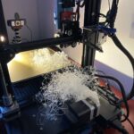 a spaghetti-print (failed 3D print) - the plate and the printer is full of white filament strings