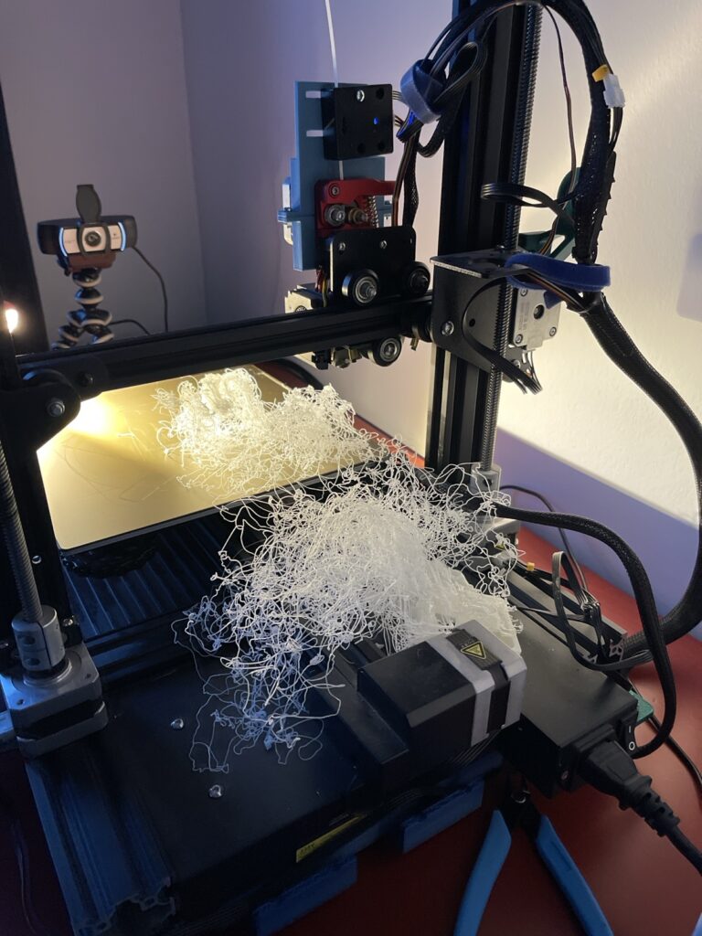 a spaghetti-print (failed 3D print) - the plate and the printer is full of white filament strings