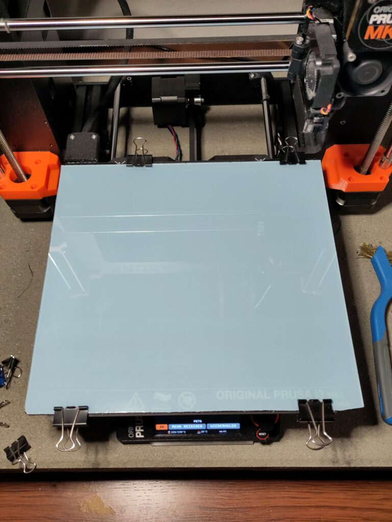 A PETG sheet clamped to the bed of a printer.
