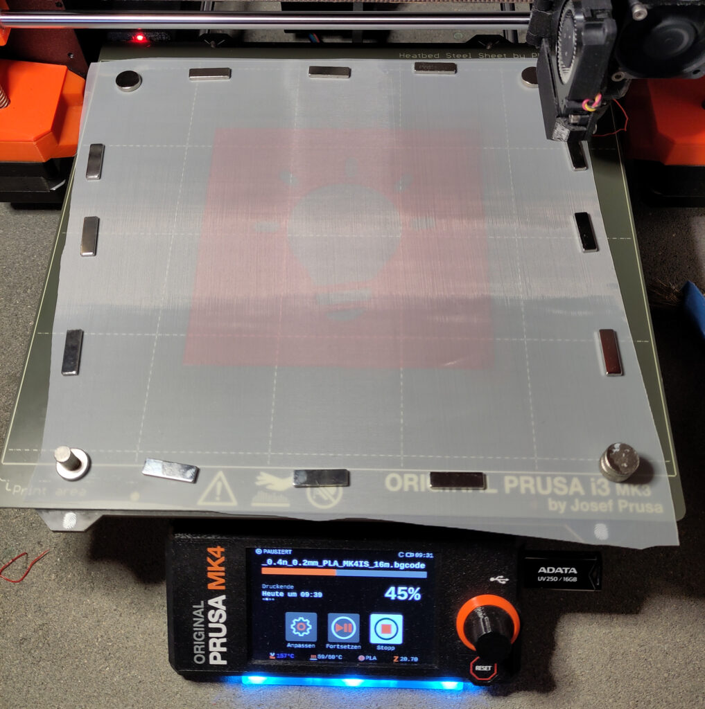 A layer of silk screen on top of an 3D-printed stencil of an lightbulb, hold in place with magnets.